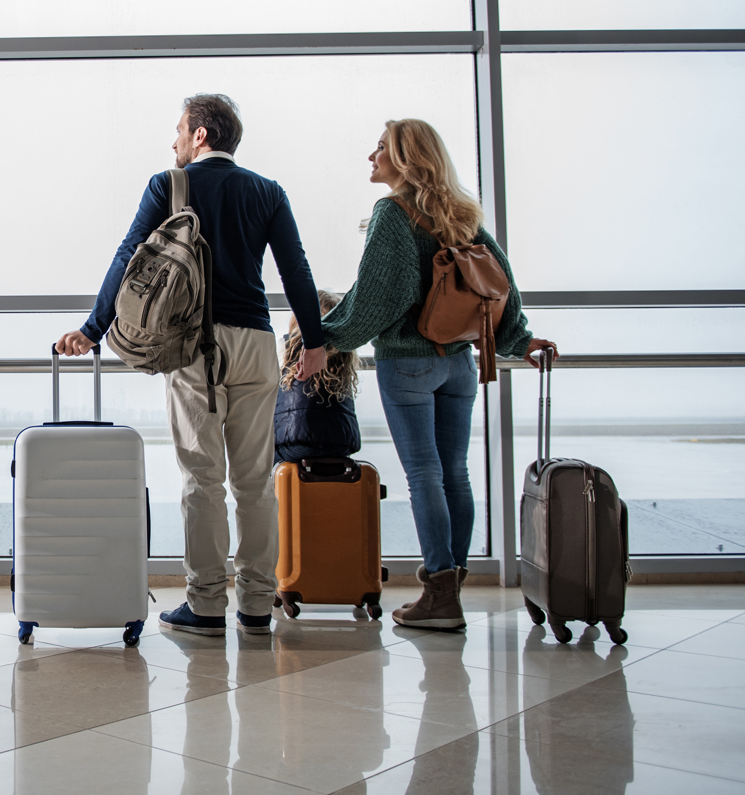 man and woman at airport with luggage looking out windows